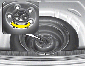 Hyundai Sonata: Removing and storing the spare tire. Turn the tire hold-down wing bolt counterclockwise.
